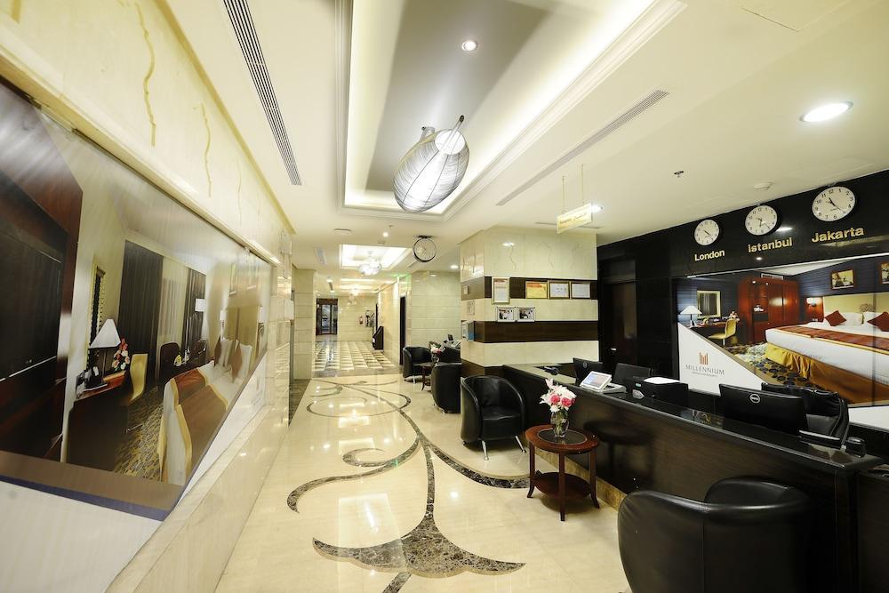 Al Aqeeq Madinah Hotel Médine Extérieur photo The photo shows the interior of a hotel lobby or reception area. It features a sleek, modern design with elegant marble flooring, decorative lighting fixtures on the ceiling, and a sophisticated color scheme. There are comfortable black seating areas
