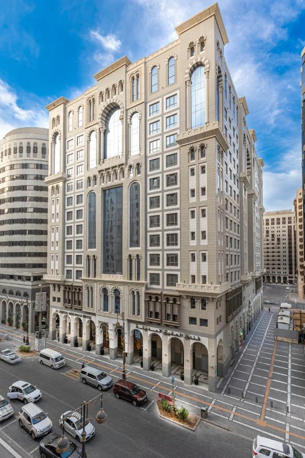 Al Aqeeq Madinah Hotel Médine Extérieur photo The photo depicts a large, modern building with a distinctive architectural style. The structure shows a blend of classic and contemporary design elements, featuring ornate details, large glass windows, and a prominent central facade. Surrounding the
