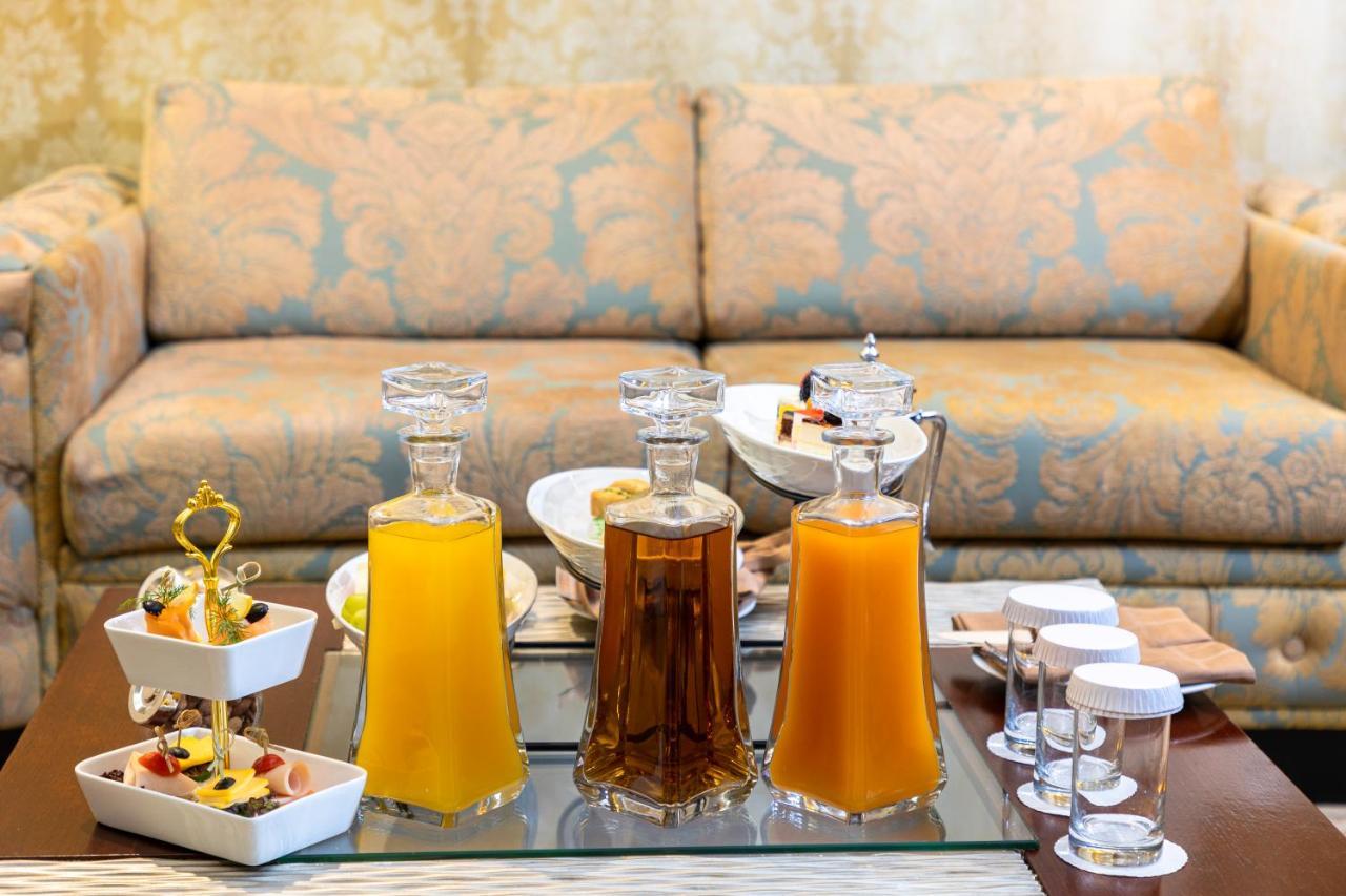 Al Aqeeq Madinah Hotel Médine Extérieur photo The photo features a beautifully arranged table with several glass decanters filled with liquids. Two decanters, one containing a yellow drink (possibly juice) and another with a darker beverage (possibly tea), are placed prominently. In front of the