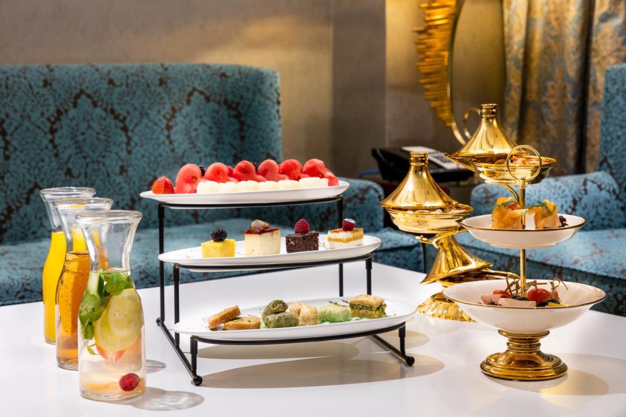 Al Aqeeq Madinah Hotel Médine Extérieur photo The photo displays an elegant dessert arrangement on a table. There are two levels of desserts: 

1. **Top Tier**: Features a selection of colorful sweets, including layers of cream or mousse desserts, garnished with fresh berries.
2. **Bottom Tier**