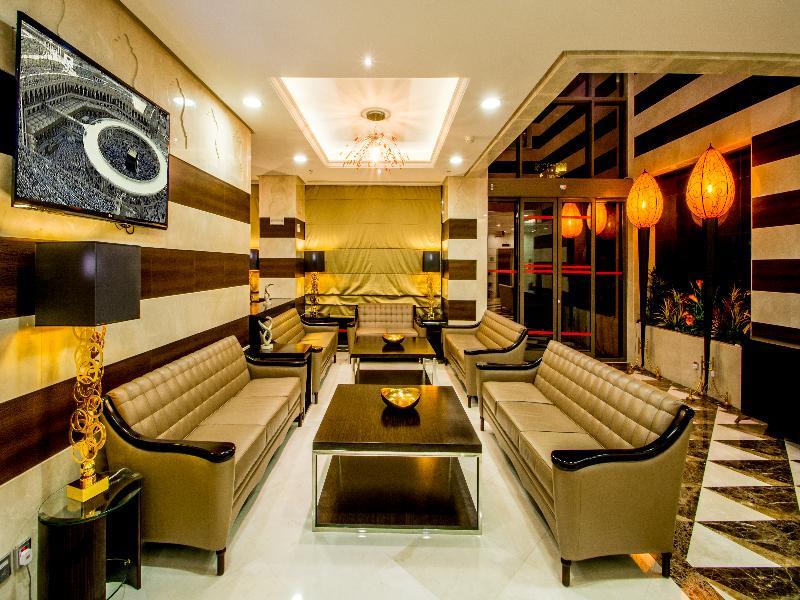Al Aqeeq Madinah Hotel Médine Extérieur photo The photo shows a modern and stylish living area or lounge. It features several beige leather sofas arranged around a central black coffee table. The walls are decorated with a mix of light colors and dark wooden accents. There is a large flat-screen