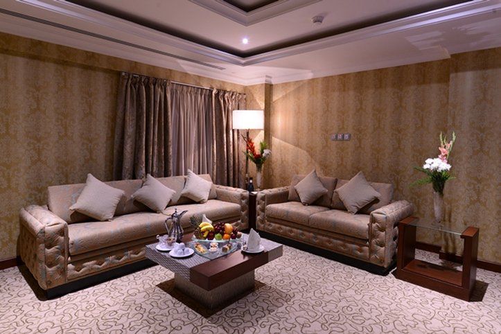 Al Aqeeq Madinah Hotel Médine Extérieur photo The photo depicts a well-decorated living room. It features two elegant sofas with decorative pillows, positioned across from each other. A coffee table is centered between them, adorned with a variety of fruits and possibly some snacks or beverages.