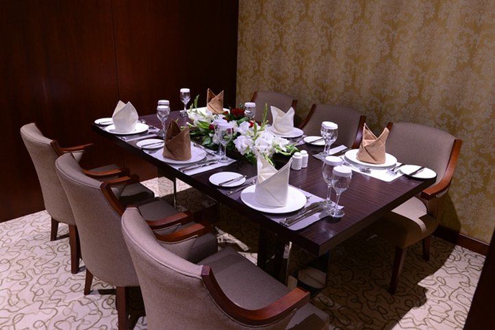 Al Aqeeq Madinah Hotel Médine Extérieur photo The photo shows an elegantly arranged dining table set for a formal meal. The table is rectangular and made of dark wood. It is adorned with white plates, glassware, and neatly folded napkins placed on top of each plate. The napkins are in two colors
